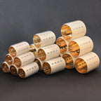 Stack of ceramic thermal hair rollers with gold and beige patterns on a dark background