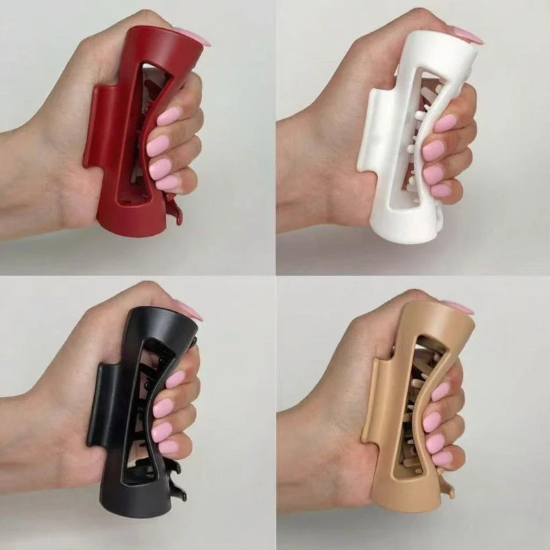 Four different colored soft silicone claw clips held by a hand on a white background