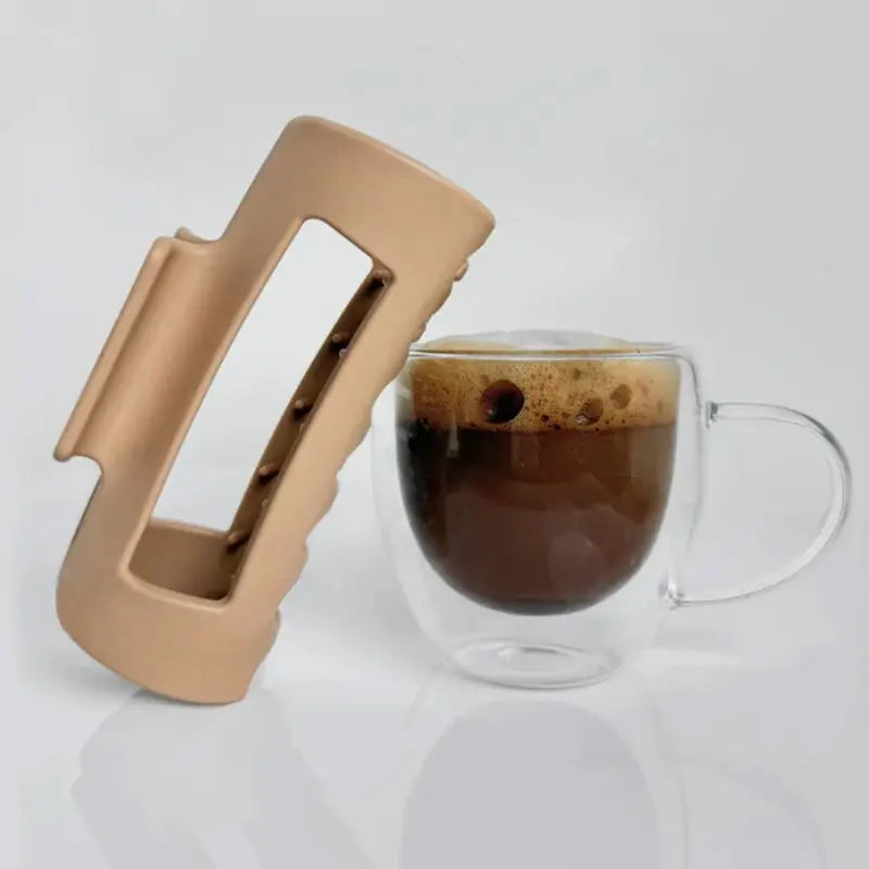 Beige silicone claw clip next to a glass mug with coffee on a white background