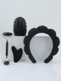 Set of black facial tools including a roller, gua sha tool, and headband on a light gray background