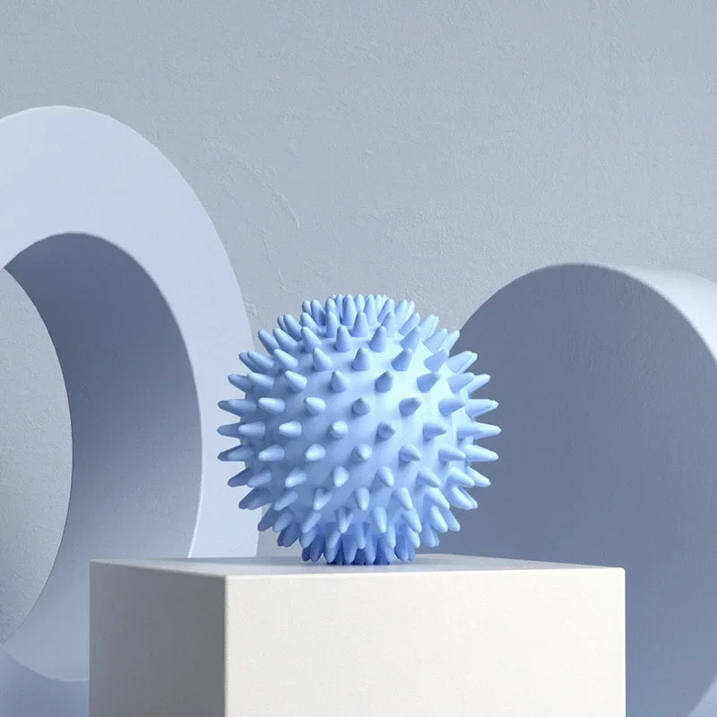 Blue textured  Spiky massage fascia ball  on a white pedestal with abstract shapes in the background