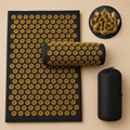 Black and gold acupressure mat set with a matching cylindrical pillow, shown alongside its black drawstring storage pouch on a beige background. A circular inset at the top right shows a close-up of the gold acupressure rose texture.