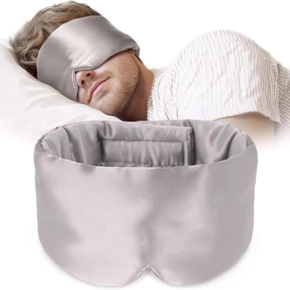 Person using a gray silk sleep mask and pillow on a white background