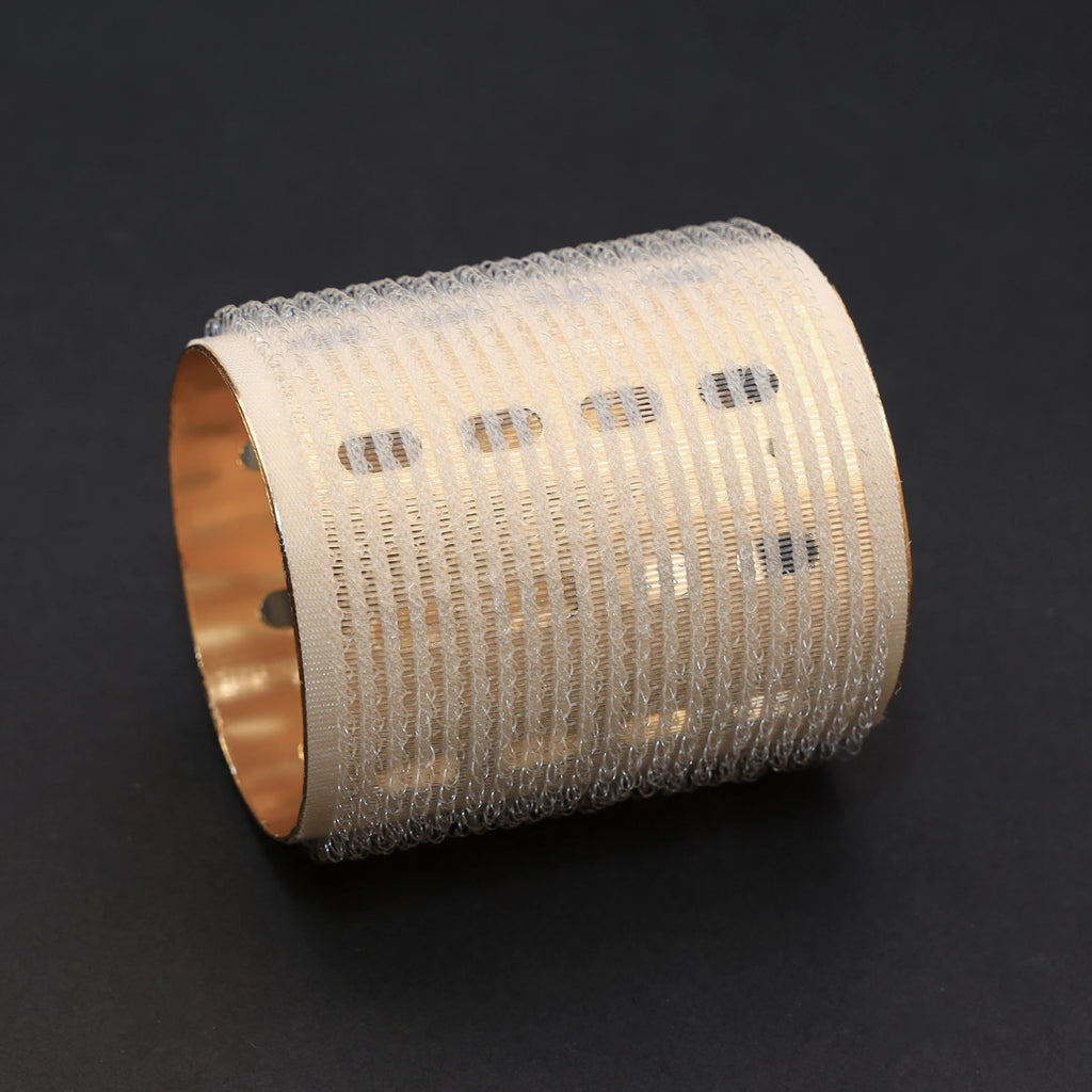 Decorative cylindrical hair roller with textured surface and gold rim on a black background