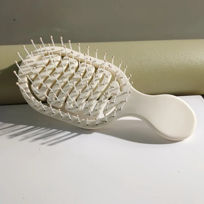 White hairbrush on a light surface with a neutral background. Mini Travel Hair Brush 