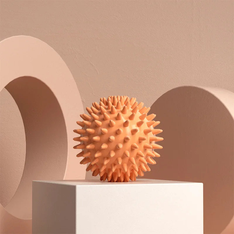 Orange Spiky massage fascia ball  on a white platform with a beige background