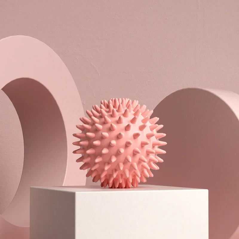 Pink textured Spiky massage fascia ball  on a white platform with a pink geometric background
