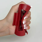 Hand holding a red silicone claw clip against a plain background