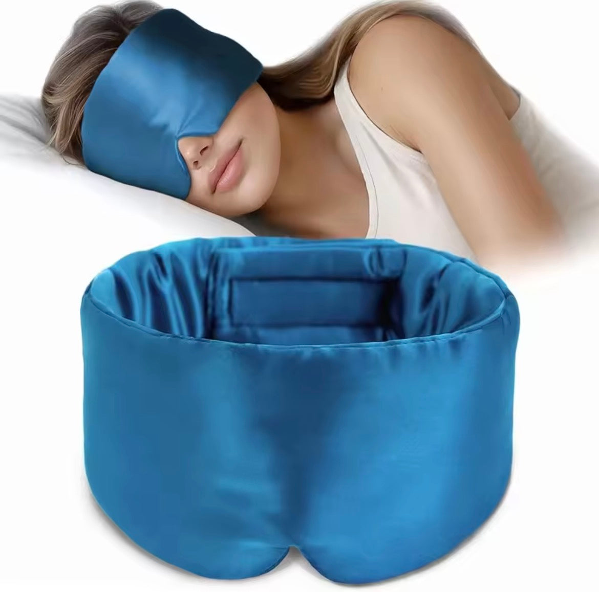 Woman wearing a silk blue sleep mask with a matching blue pillow on a white background