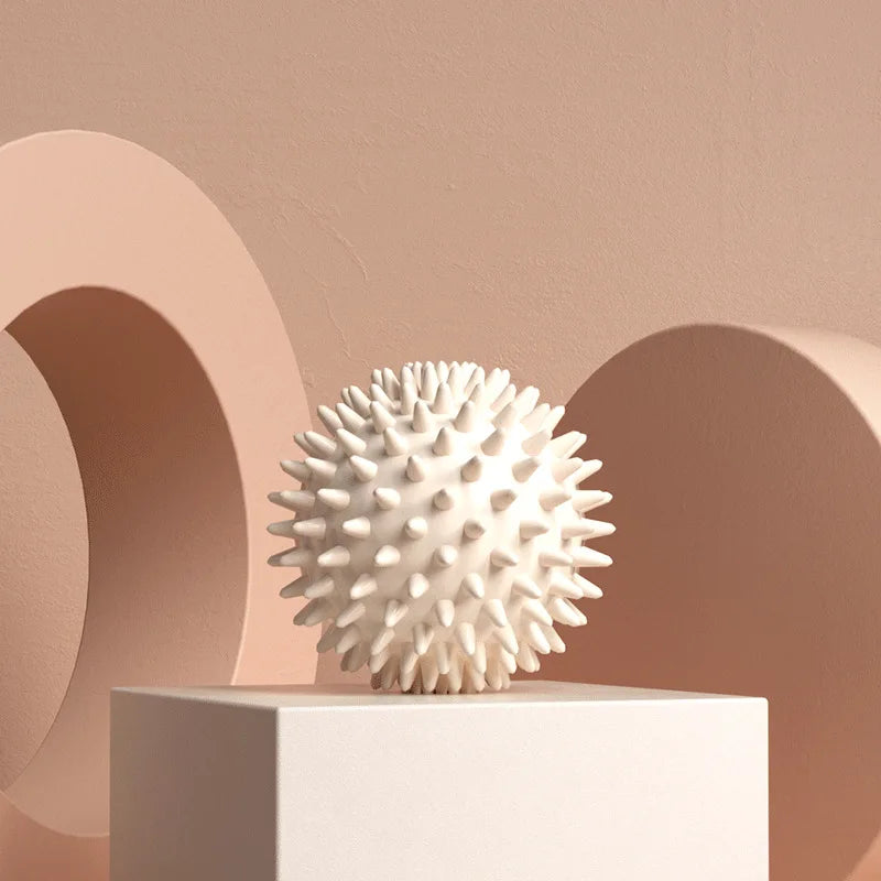 White textured  Spiky massage fascia ball  on a white pedestal against a beige background