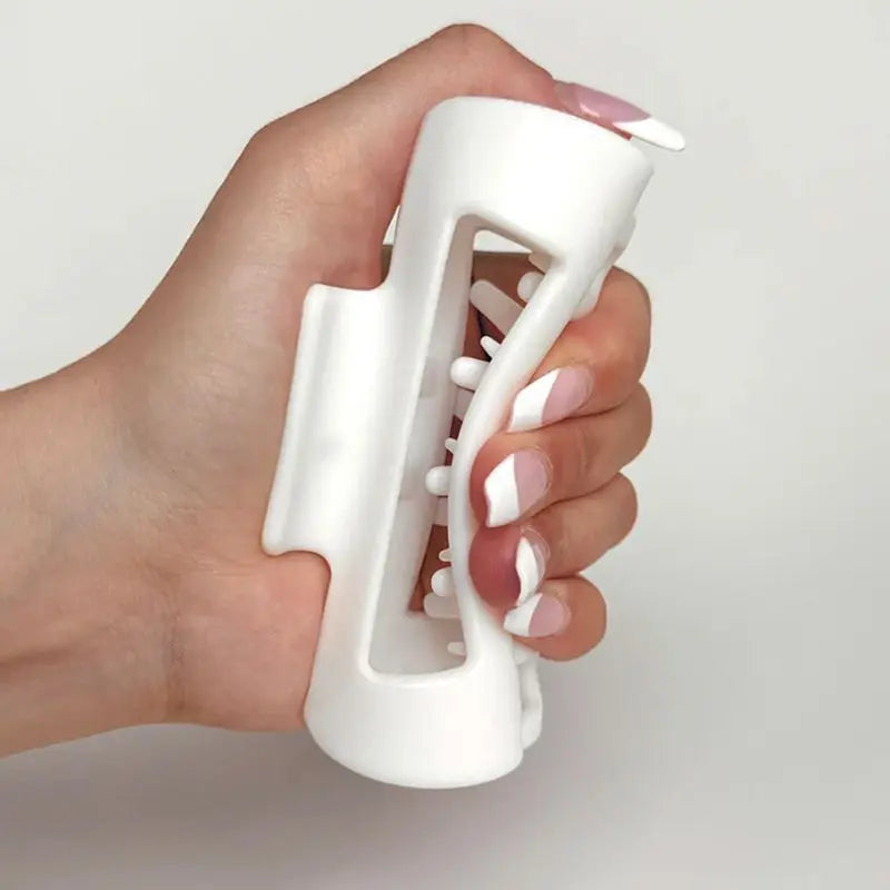 Hand holding a white silicone claw clip against a plain background