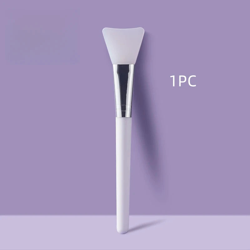 White facial mask brush with silver head on a purple background